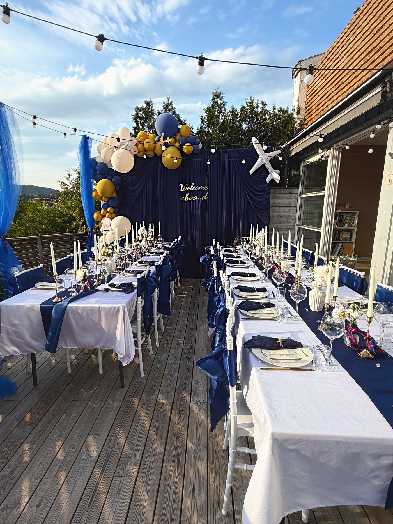 Terrasse dekket til flytema-feiring med lyslenker og ballongbue